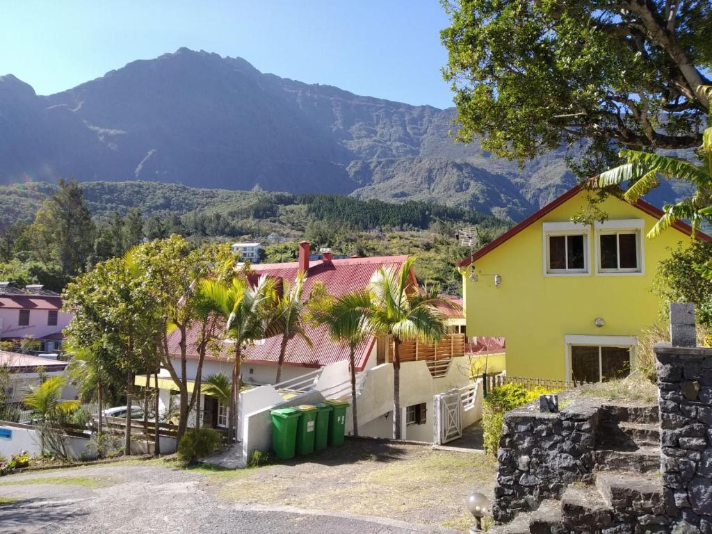 a yellow house with a mountain in the background at TiCaze MONTAGNE in Cilaos