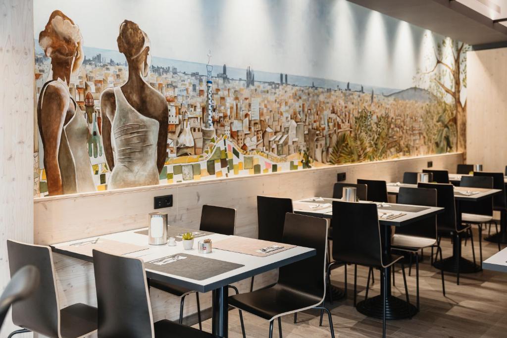 un ristorante con tavoli e sedie e un grande murale di Hotel Travessera a Barcellona