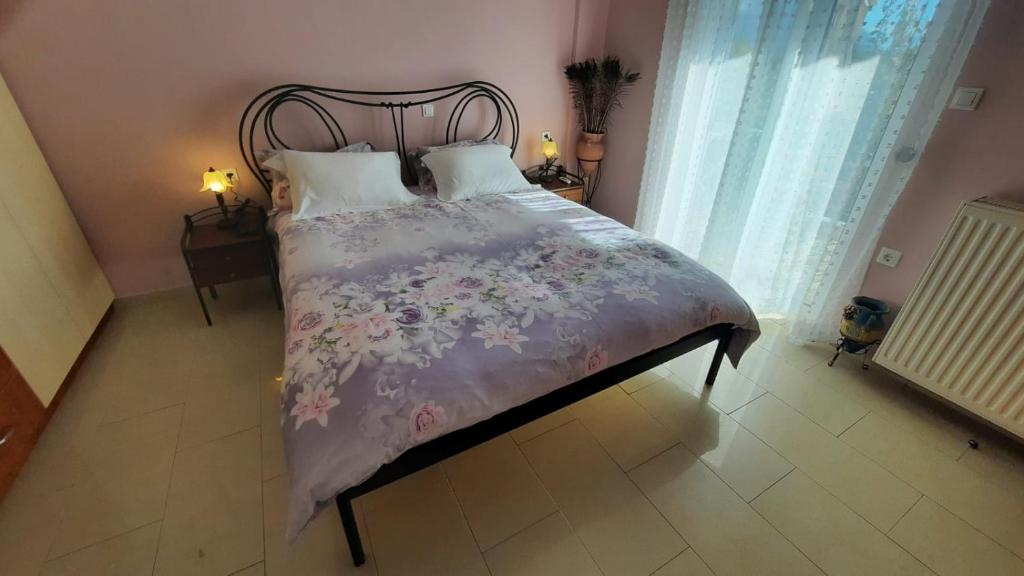 a bedroom with a bed with a floral bedspread at IOANNIS - Room with balcony near Limnopula in Gavrolímni