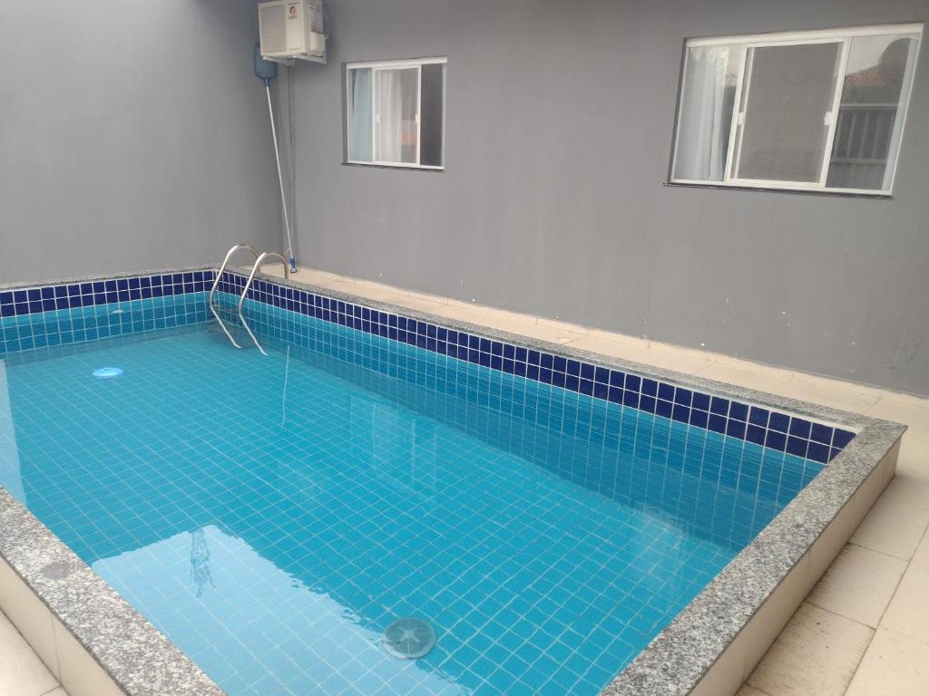 a swimming pool with blue tiles on the floor at Temporada Precisão Beta in Arraial do Cabo