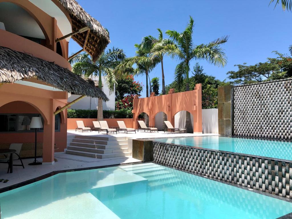 a swimming pool in a house with chairs and palm trees at New Nautilus Lodge in Puerto López