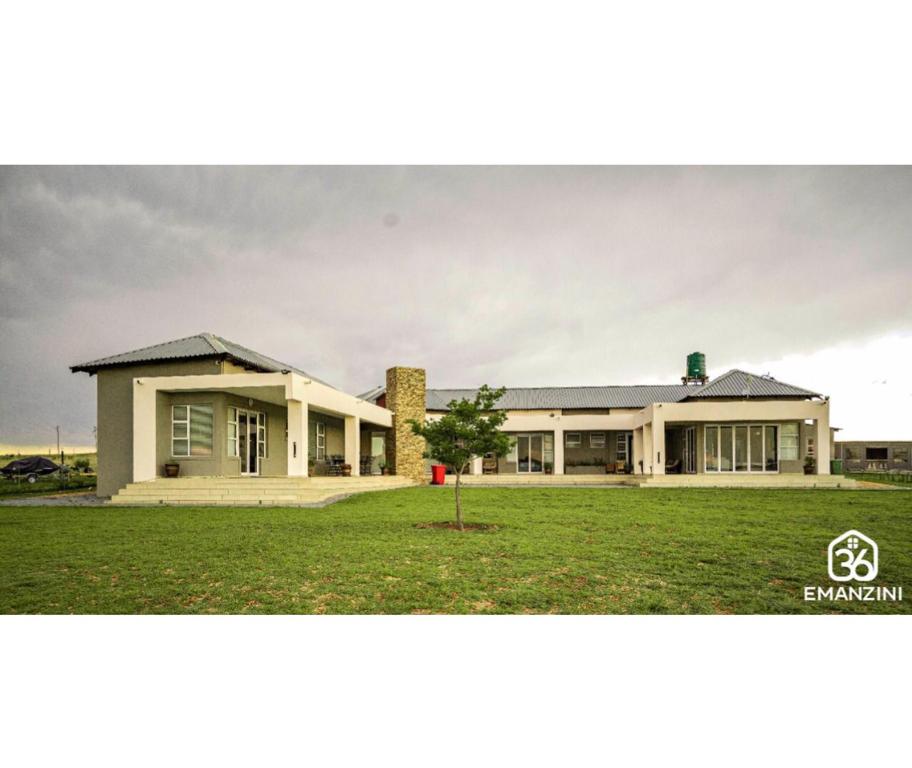 a large building with a grass field in front of it at 36 Emanzini (Holiday home lake view) in Denysville