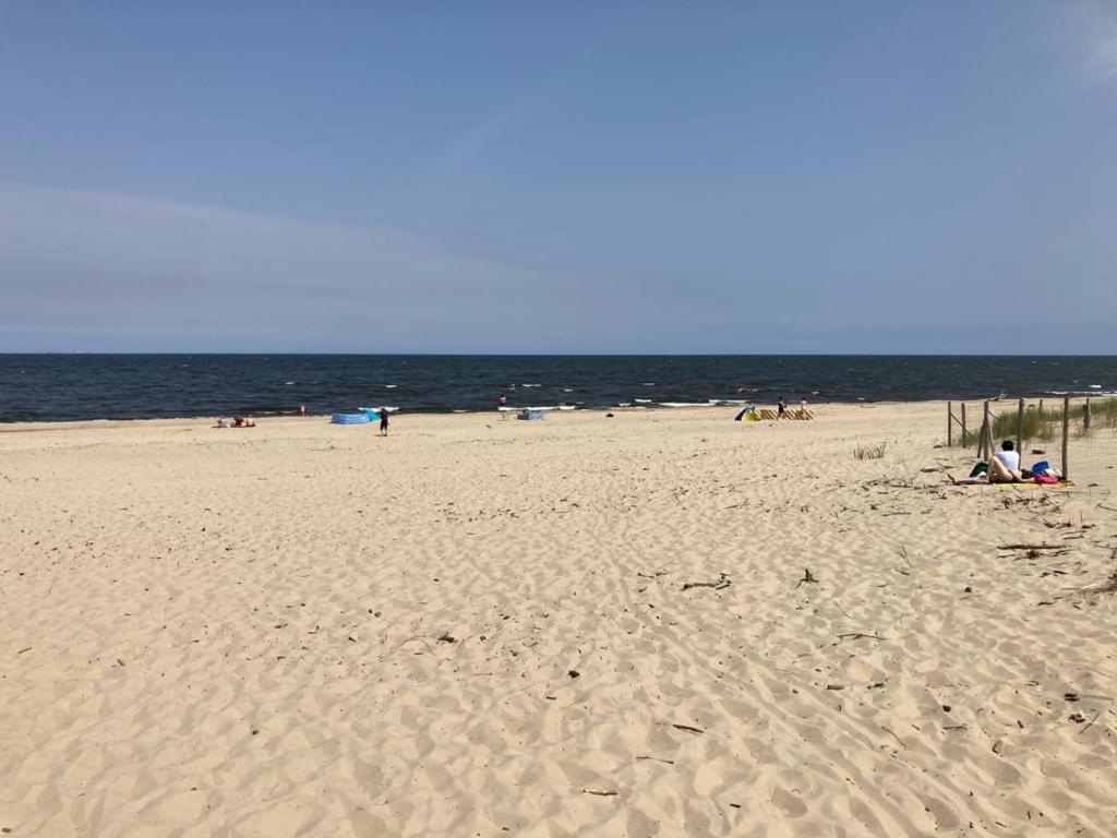 a beach with people sitting on the sand and the ocean at Lazur Park Kotwica in Gdańsk