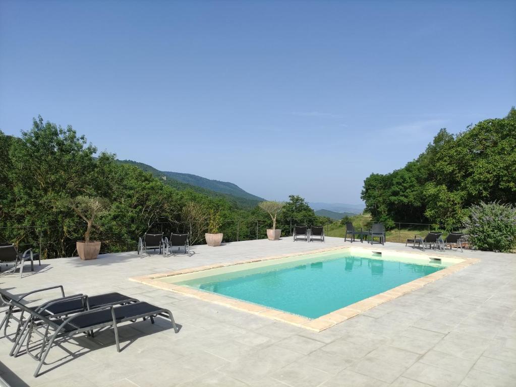 a swimming pool with chairs and a table at Les Jardins de Soulane B&B - Adults only in Belcastel-et-Buc