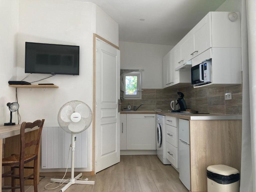 坎城的住宿－studio maisonnette de vacances，厨房配有白色橱柜和风扇