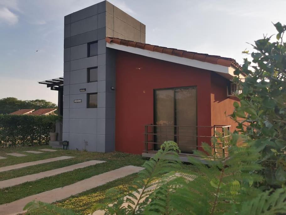 ein kleines Haus mit einem roten Gebäude im Hof in der Unterkunft Playa Tamarindo, CasaMar de Tamarindo in Tamarindo