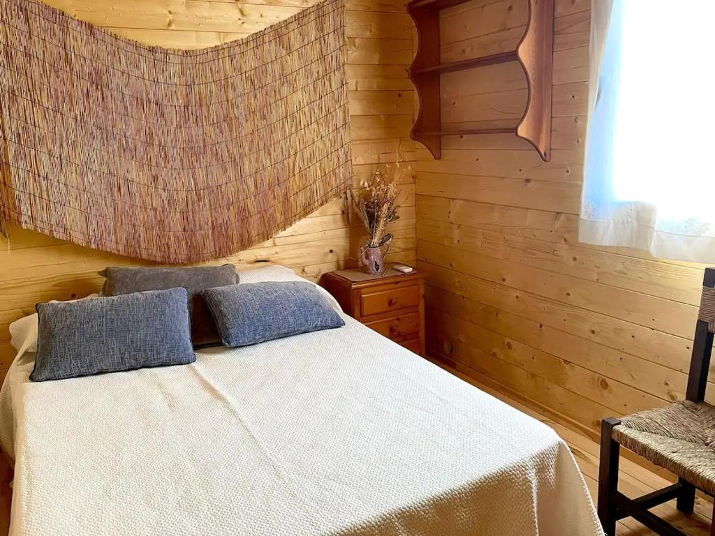 a bedroom with a white bed and a wooden wall at Dos VILLAS ENTRE CIERVOS Y CERVANTES in El Cristo del Espíritu Santo