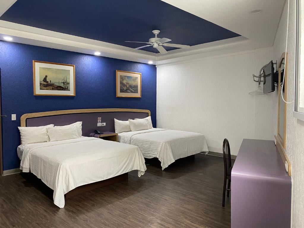 a bedroom with two beds and a blue wall at Hotel Menara in Mexico City