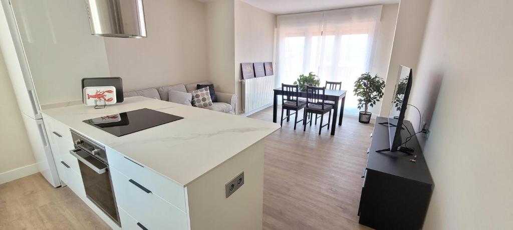 una cucina con bancone bianco e un soggiorno di SANNIKO APARTMENT Ático con Terraza a Getxo