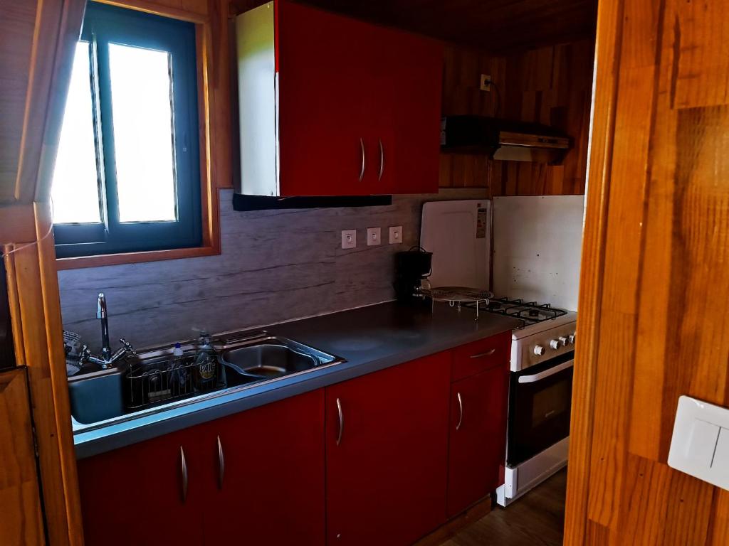 a kitchen with red cabinets and a sink and a stove at La roulotte géante in Le Tampon