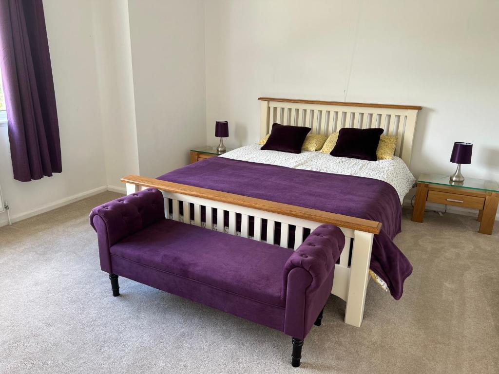 スウォンジーにあるGower Getaway - Parking & Ensuiteのベッドルーム(ベッド1台、紫色のソファ付)