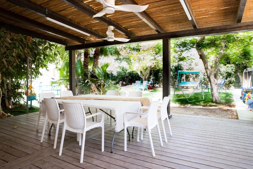une table à manger blanche et des chaises sur une terrasse dans l'établissement רגע ערבה, à ‘En Yahav