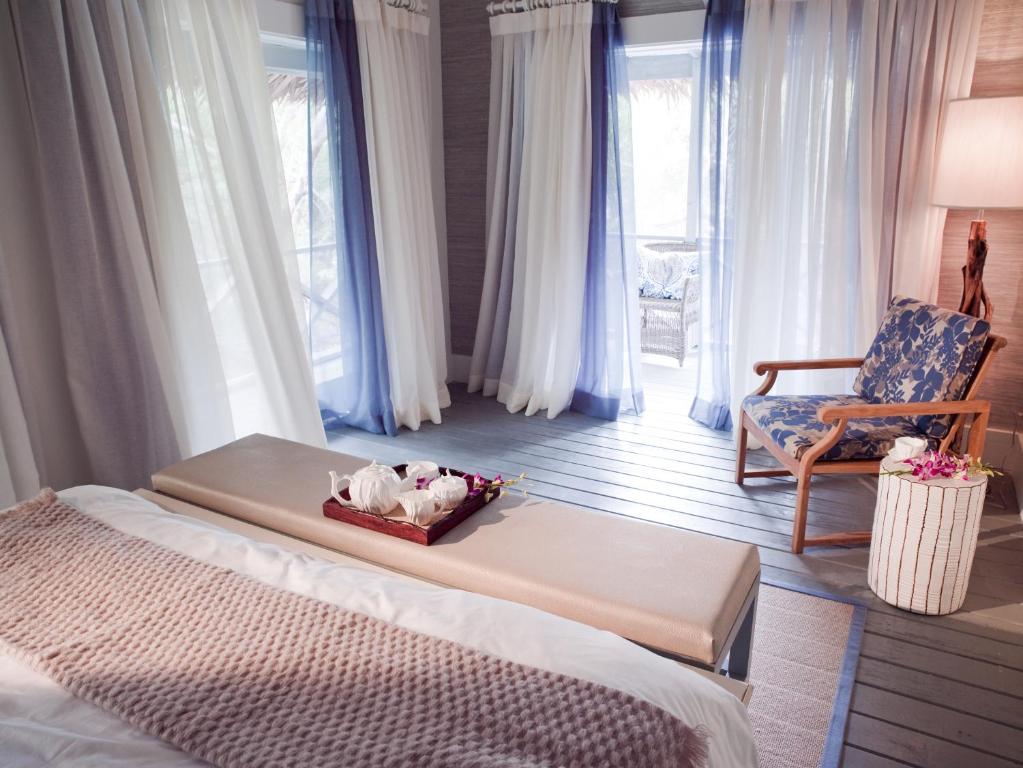 a bedroom with a bed and a chair and a bed and window at Tiamo Resort in Kemps Bay