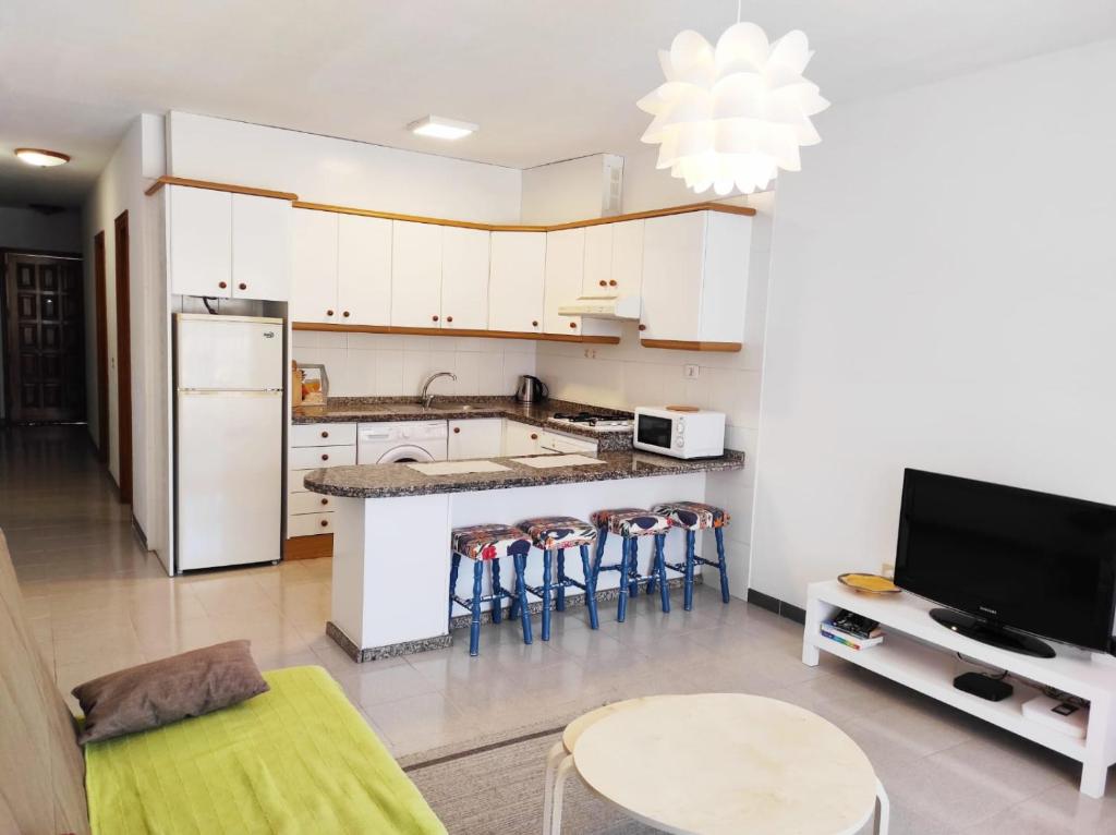 una cucina con mobili bianchi, tavolo e sedie di Almichara a El Médano