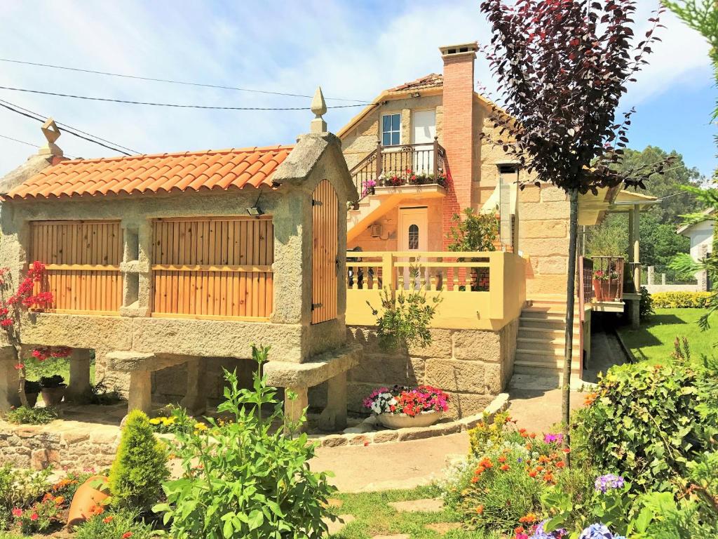 a house with a balcony and a yard with flowers at Casa Turistica Nigrán in Nigrán