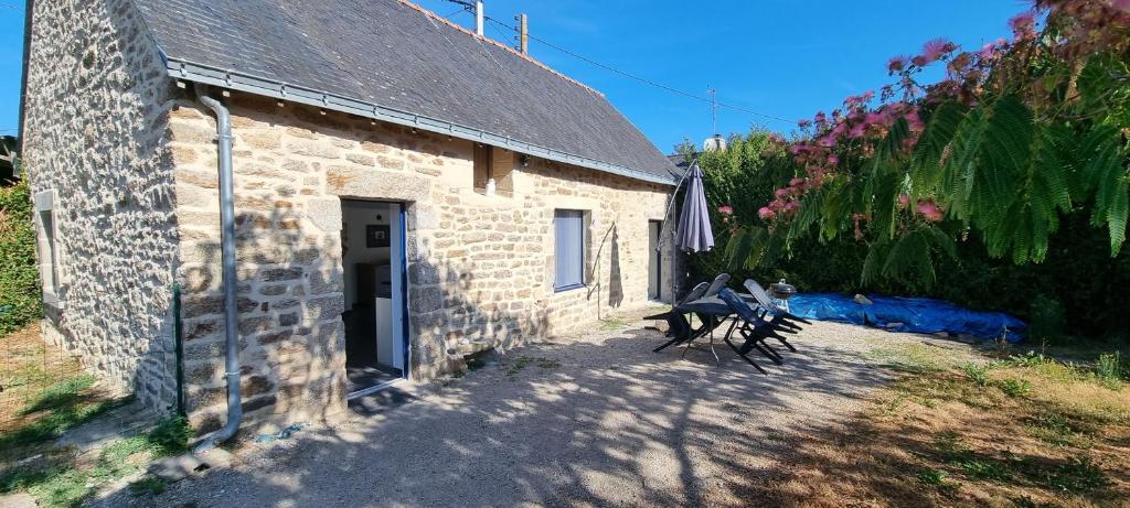 un edificio de piedra con dos bancos delante en Location vacances Morbihan Questembert, en Questembert