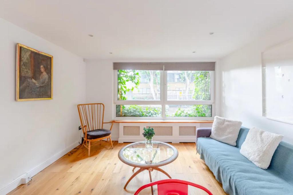 uma sala de estar com um sofá azul e uma mesa de vidro em Spacious 1 Bedroom Apartment in Vibrant Angel em Londres