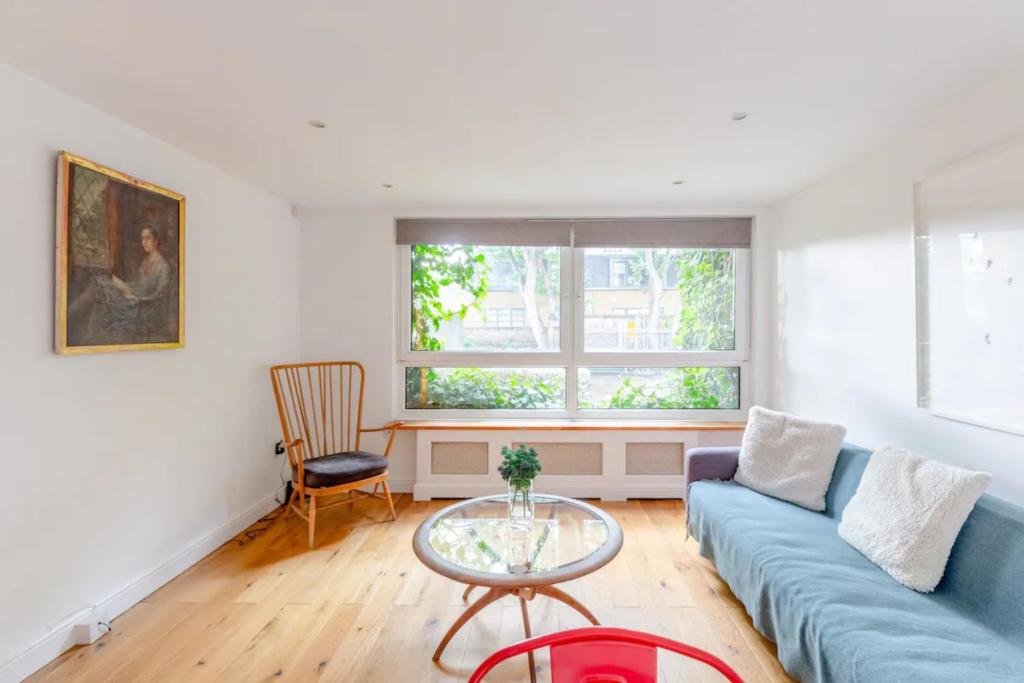 a living room with a blue couch and a glass table at Spacious 1 Bedroom Apartment in Vibrant Angel in London