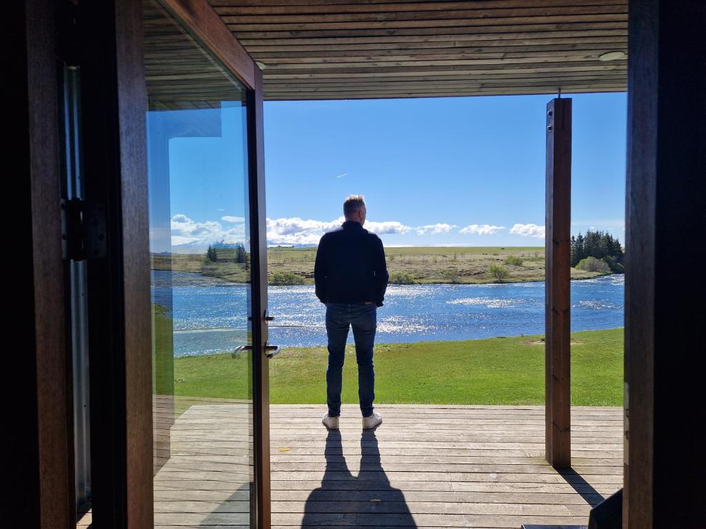 a man standing on a porch looking out at the water at West Ranga lodge in Hella