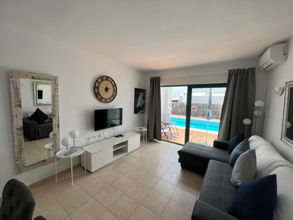 sala de estar con sofá, TV y espejo en Oasis Blue - beautiful 1 bedroom apartment on private complex with pool en Tías