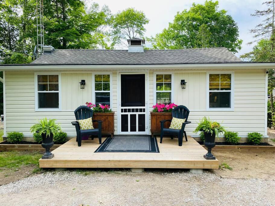 uma casa com duas cadeiras num deque de madeira em Sauble Shores Waterfront Hideaway em Sauble Beach