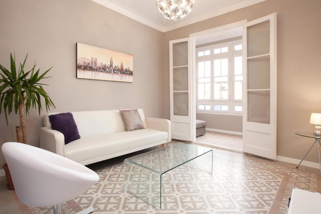 een woonkamer met een witte bank en een glazen tafel bij Enjoy Apartments Borrell in Barcelona