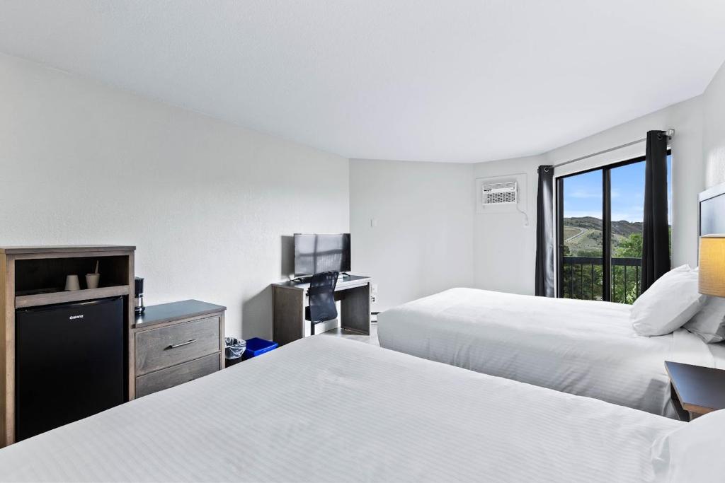 a hotel room with two beds and a desk at The Vista Inn in Kamloops
