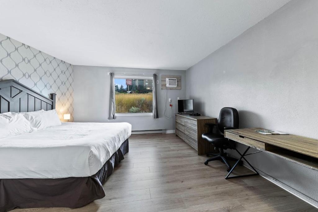 a bedroom with a bed and a desk and a computer at The Vista Inn in Kamloops