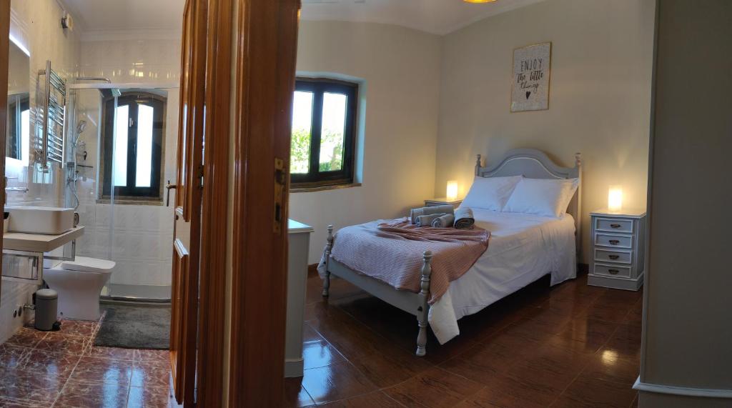 a bedroom with a bed and a bathroom with a sink at Casa Além Rio - quartos para 6 hóspedes em Santo Tirso in Santo Tirso