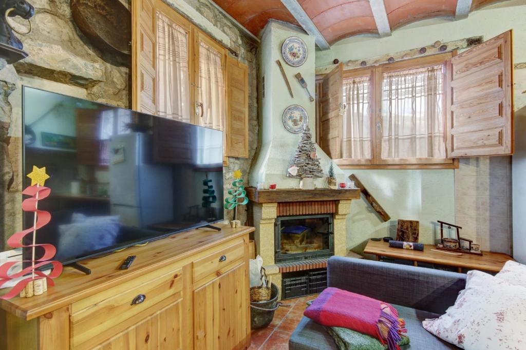 een woonkamer met een grote televisie en een open haard bij Can MartiPol in La Pobla de Lillet
