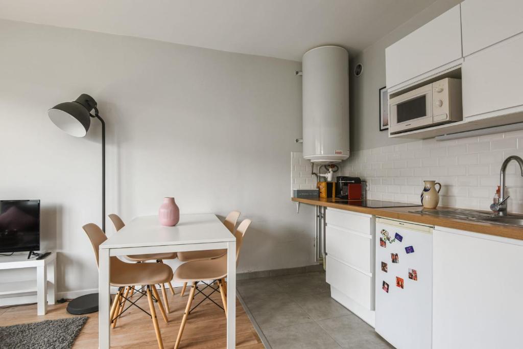 a kitchen with white cabinets and a table and chairs at Beautiful apartment with a balcony in the heart of Lille - Welkeys in Lille