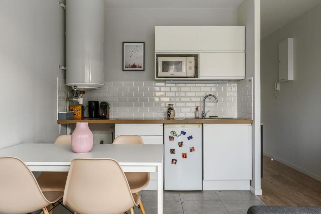 a kitchen with white cabinets and a table and chairs at Beautiful apartment with a balcony in the heart of Lille - Welkeys in Lille