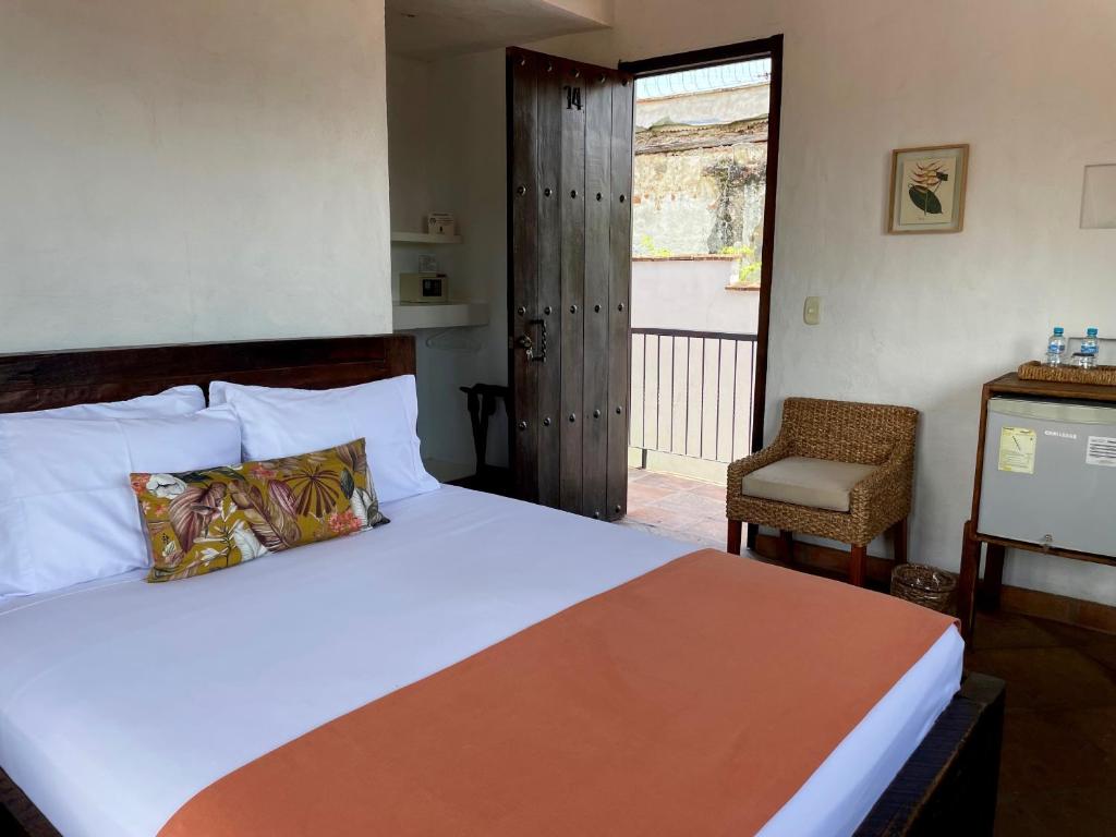 a bedroom with a bed and a chair and a window at Hotel Boutique Posada Las Trampas in Honda