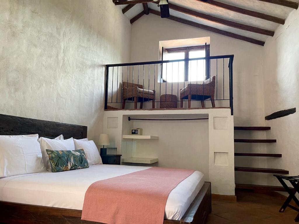 a bedroom with a bed and a balcony with chairs at Hotel Boutique Posada Las Trampas in Honda