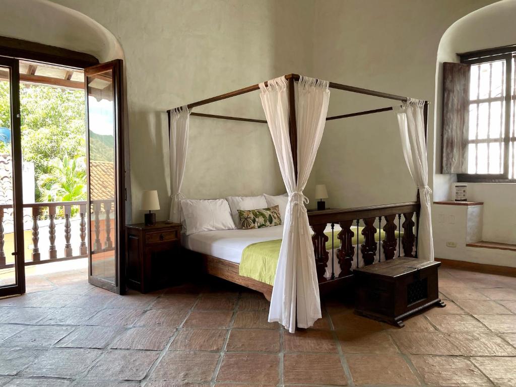 a bedroom with a canopy bed and a balcony at Hotel Boutique Posada Las Trampas in Honda