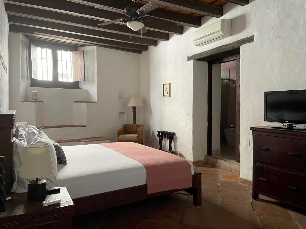 a bedroom with a bed and a flat screen tv at Hotel Boutique Posada Las Trampas in Honda