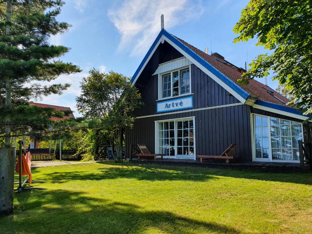 een huis met een blauw dak bij Waterfront Villa Artvė with sauna - self check-in in Pervalka