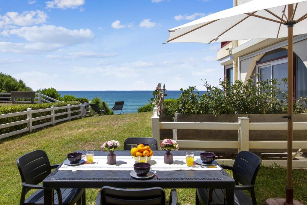 ein Tisch mit einem Regenschirm und der Ozean im Hintergrund in der Unterkunft Wonderful apartment with direct access to the beach - Bidart - Welkeys in Bidart