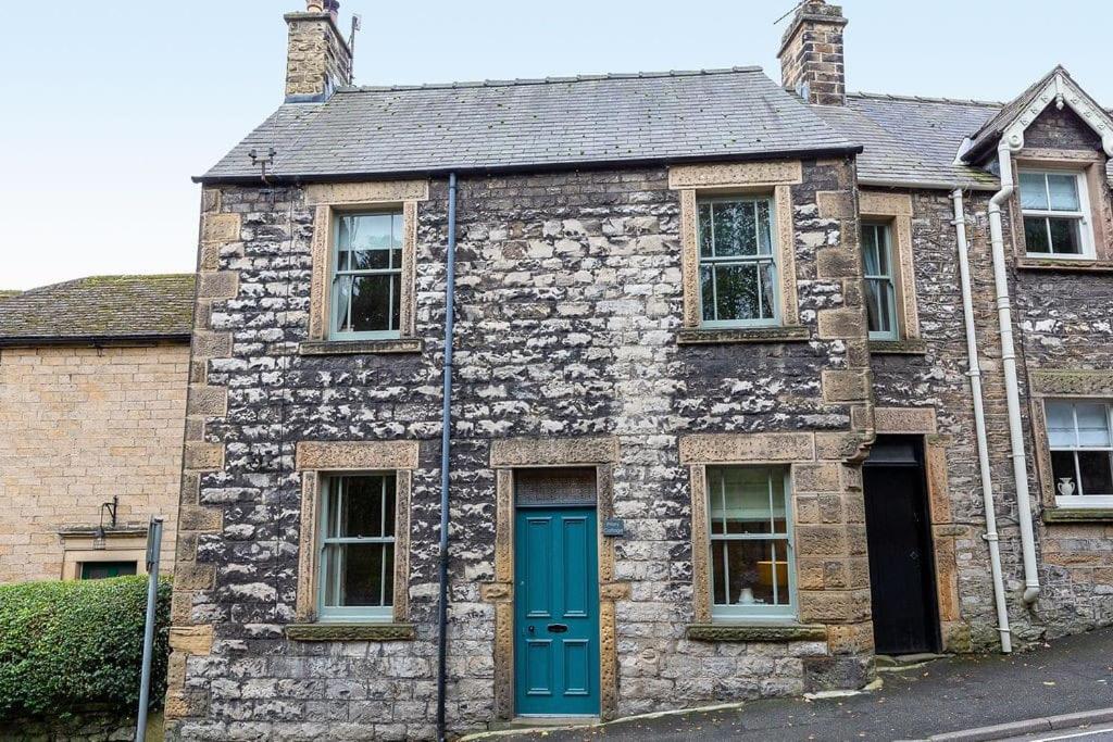 an old stone house with a blue door at Cosy cottage in the heart of Bakewell in Bakewell