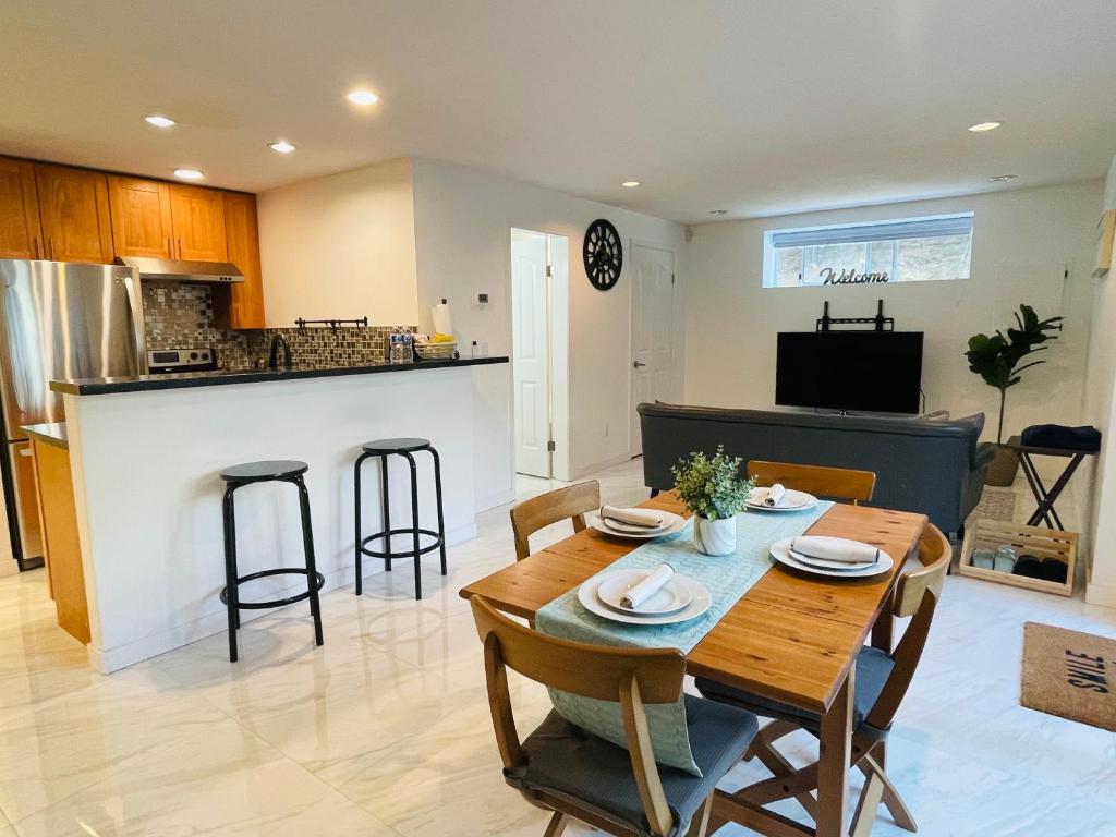 a kitchen and living room with a wooden table and chairs at Adorable 2-Bedroom Basement in Vancouver in Vancouver