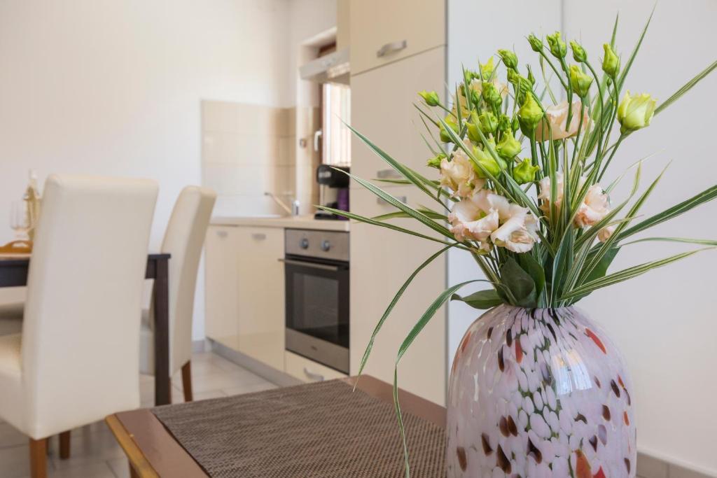 un jarrón con flores sobre una mesa en una cocina en Apartmani Xenia & Desiderio, en Buzet