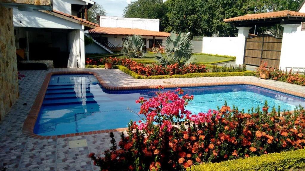 a swimming pool in a yard with flowers at Finca La Martinoza Rozo in Rozo