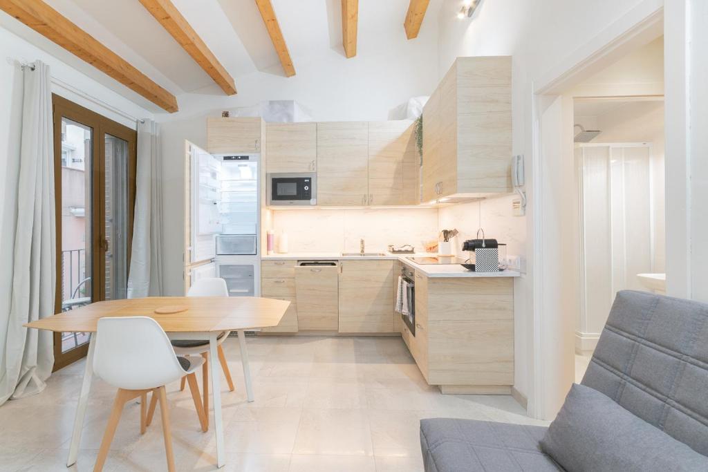 Il comprend une cuisine et une salle à manger avec une table et des chaises en bois. dans l'établissement NICE CITY CENTER APARTMENT, à Vilanova i la Geltrú