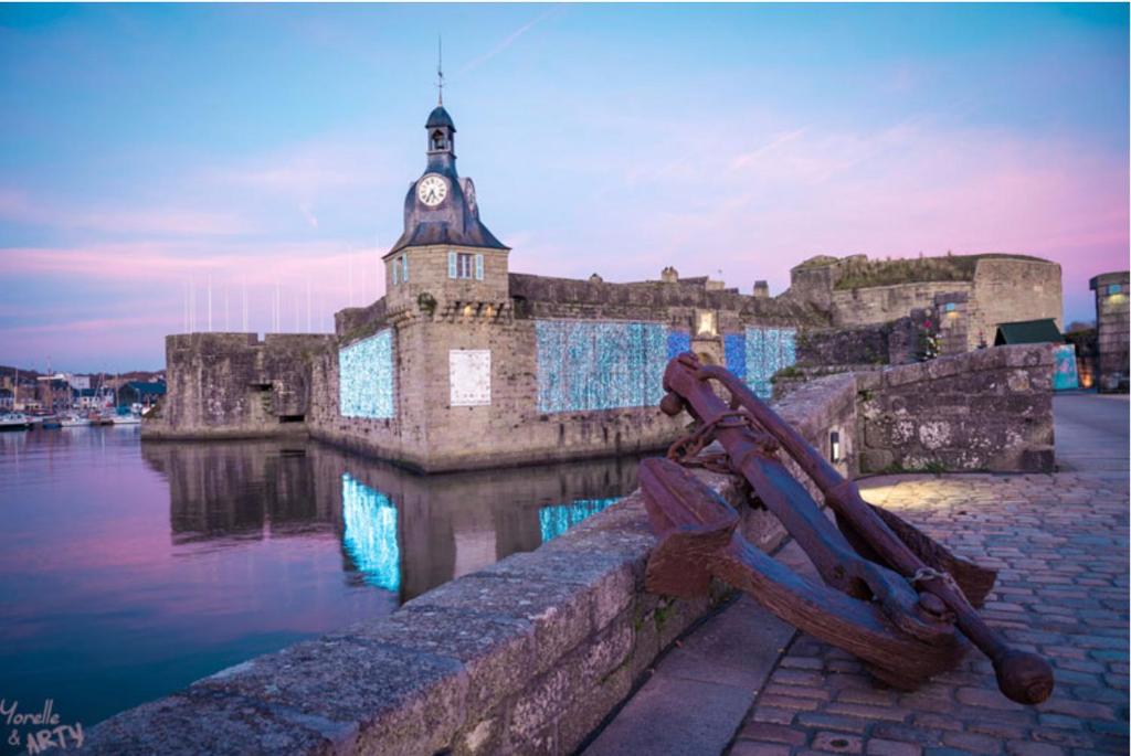 un bâtiment avec une tour d'horloge à côté de l'eau dans l'établissement Yvana, à Concarneau