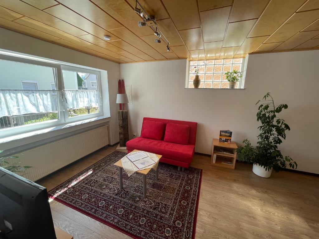 a living room with a red chair and a table at Oxtown City Apartment in Ochsenhausen