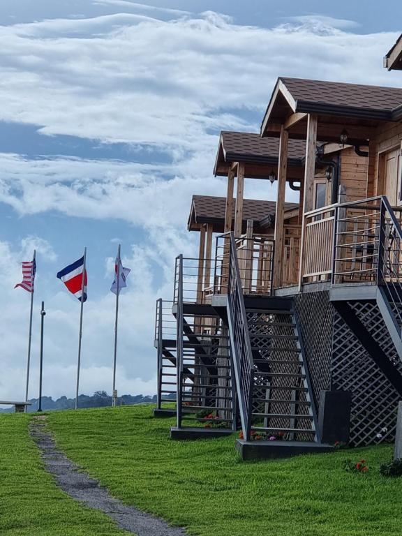 a building with stairs and flags on a grass field at Hotel Cabañas y Mirador Secret Garden CR in Cartago