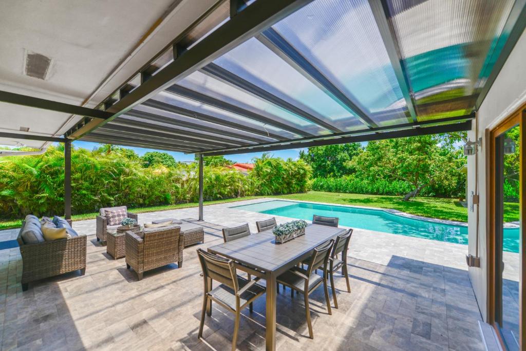 um pátio com uma mesa e cadeiras e uma piscina em Awesome 4 Bedroom HouseW/Pool @Westchester Miami em Tamiami