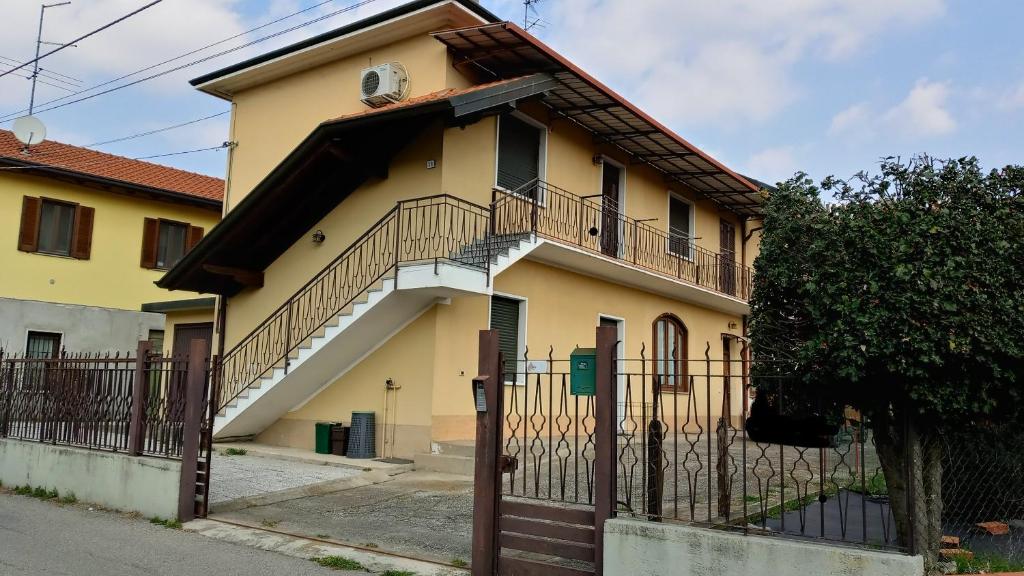 żółty dom z balkonem i ogrodzeniem w obiekcie Appartamento Kiwy w mieście Arsago Seprio