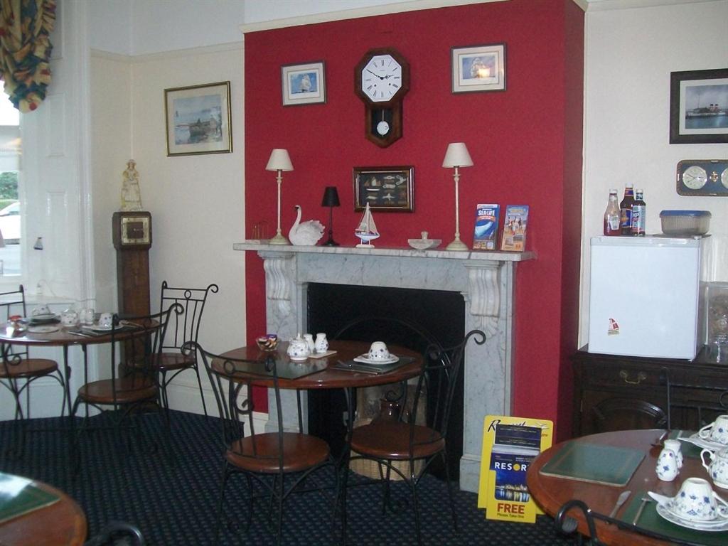 a room with a fireplace and tables and a clock at Boaters Guesthouse in Weymouth