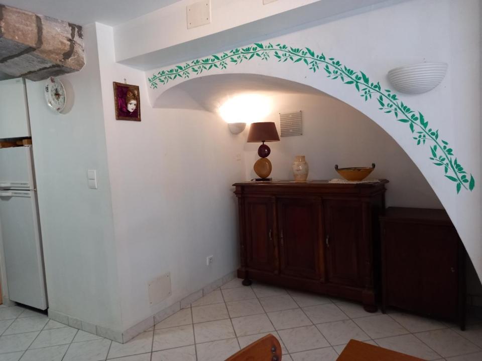 an archway in a kitchen with a table and a refrigerator at charmante maison de village in Saint-Jean-du-Bruel